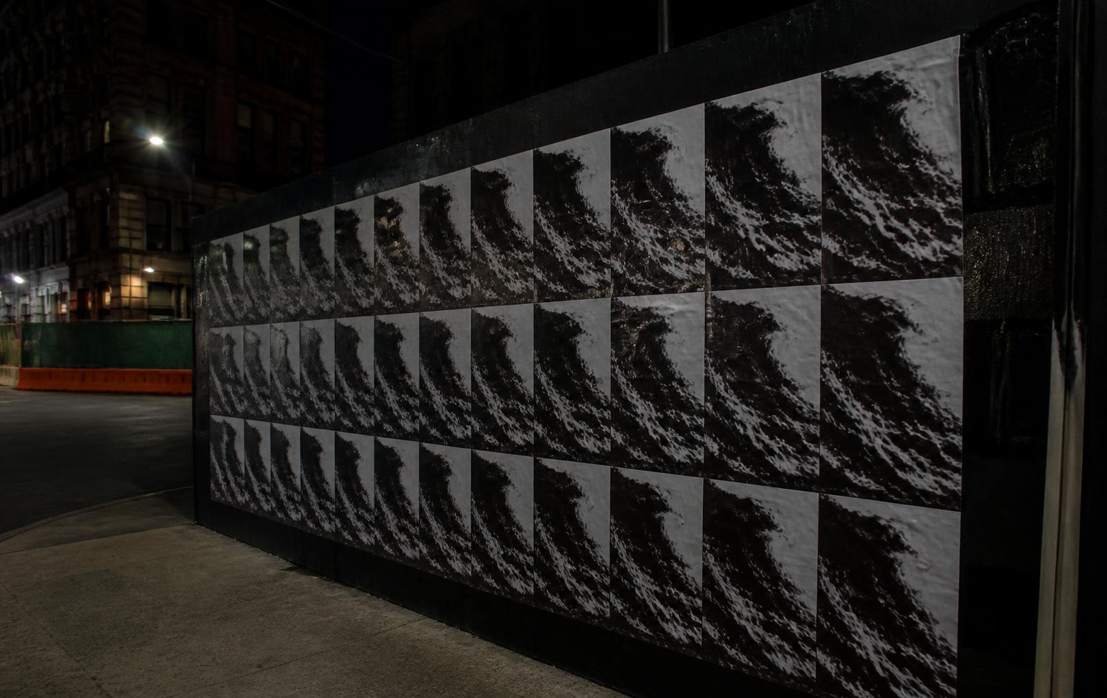 A city wildposting campaign of monochrome wave posters at night